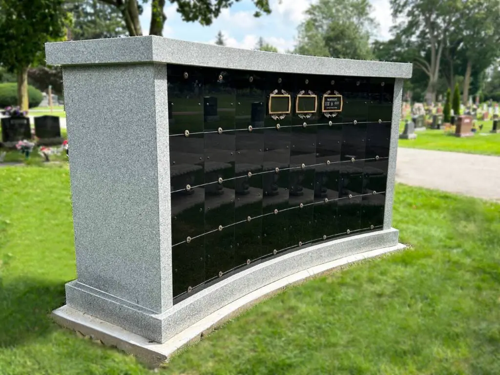 A single curved 32-niche columbarium shown sitting within roughly the same footprint as a single in-ground burial plot