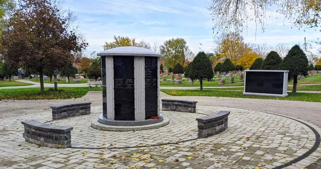 A columbarium surrounded by stone benches in a cemetery